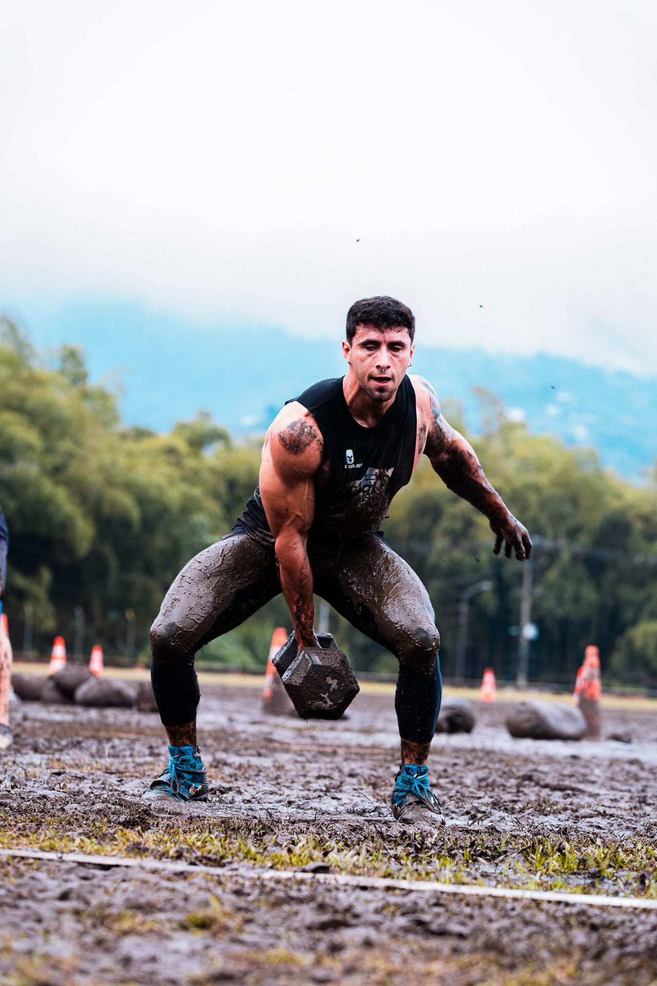 A mixed group pushing through a mud-filled outdoor fitness challenge.