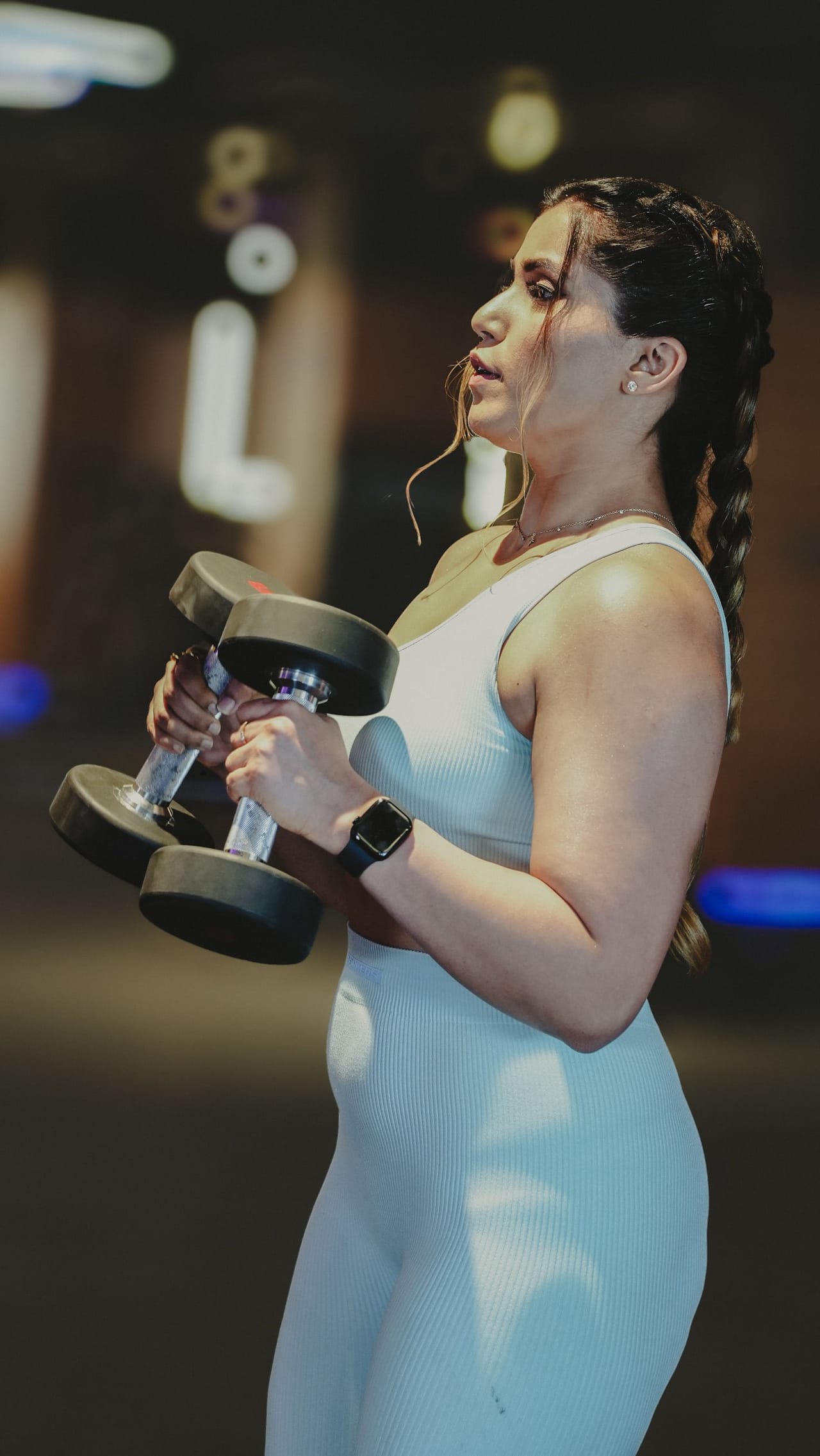 An athlete working through a dumbbell set under coaching supervision.